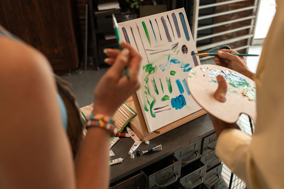 Two artists painting an abstract artwork in a studio, sharing creative techniques.